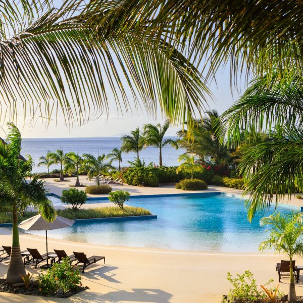 Infinity pool at InterContinental Dominica surrounded by palm trees and lounge chairs, with ocean views in the background